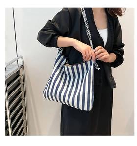 Detail der blau-weiß gestreiften Canvas-Tasche mit geometrisch gewebtem Schultergurt