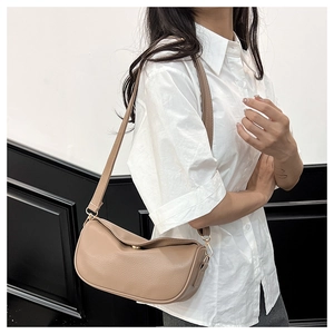 Detailed side view of the khaki crescent crossbody bag worn by a model in casual attire