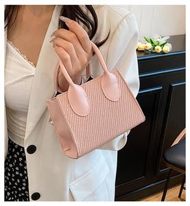 Dettaglio di una mini borsa rosa chiaro con trama intrecciata e manico in pelle liscia