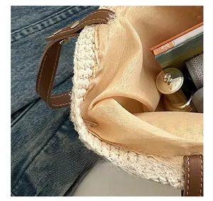 Dettaglio della borsa tote in maglia beige con manici in pelle marrone e fodera in rete