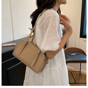 Detail of khaki leather shoulder bag with decorative buckle straps and metal zipper