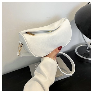 Detail view of the white lychee grain texture and gold metal hardware on the half-moon bag