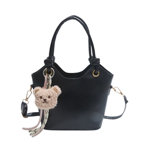 Minimalist black leather bucket bag with top handle and cute plush bear charm accessory