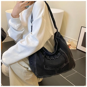Détail du sac hobo en jean noir avec bords effilochés et coutures contrastées blanches