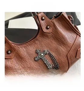 Vue détaillée du sac en cuir marron avec breloque croix en métal et rivets cloutés