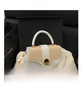 Detail view of the elegant geometric hardshell box bag with straw patchwork and gold latch