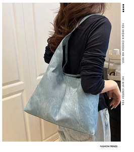Detailed close-up of light blue hobo bag with textured matte leather finish and wide strap