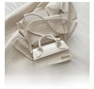 Detailed macro view of white crocodile pattern texture and metal logo on handbag