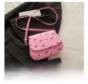 Detailed view of pink cherry print PU leather crossbody bag on a black blazer