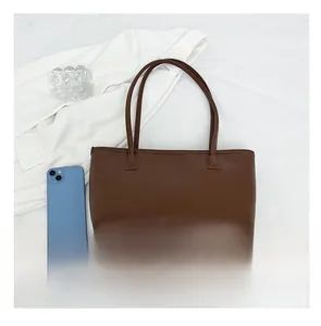 Detail view of large dark brown tote bag capacity shown with a smartphone comparison