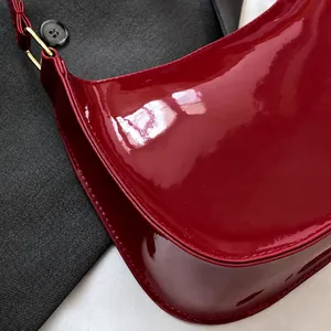 Dettaglio della borsa a spalla in pelle verniciata rossa con fibbie in metallo dorato