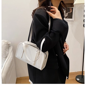 White rectangular leather shoulder bag with FASHION & BAG print held by model in black blazer