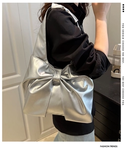 Detailed view of large silver metallic bow shoulder bag with glossy reflective finish