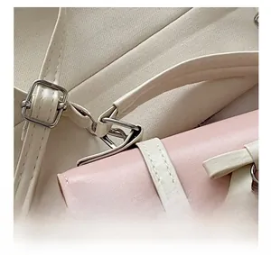Detail shot of the butterfly lock hardware and stitching on pink and white crossbody bag