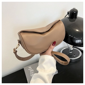 Close-up of khaki dumpling bag in lychee pattern leather held by model in lifestyle setting