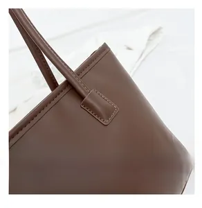 Close-up of reinforced double stitching on the dark brown leather tote bag handle
