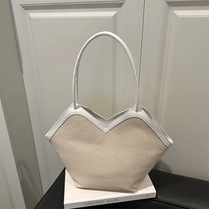 Minimalist beige woven tote bag with white leather straps and unique V-shaped top design