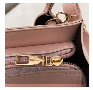 Dettaglio della cerniera in metallo dorato e trama in pelle rosa della borsa a tracolla