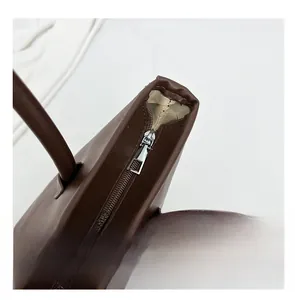 Detail of smooth silver zipper closure on a vintage dark brown large capacity tote bag