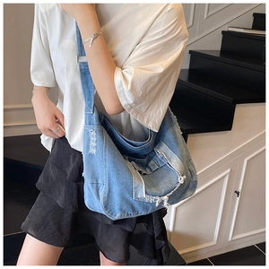 Detail of distressed denim tote bag featuring vintage frayed edges and a wide strap