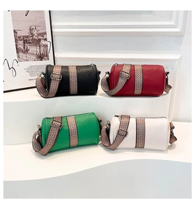 Detail of four colorful leather cylinder bags with wide woven straps on a white stand