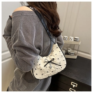 Detail of seersucker underarm bag with black bows and silver heart charm on model