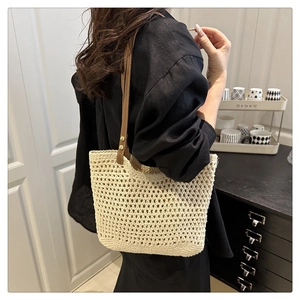 Dettaglio della borsa tote beige intrecciata a mano con manici in pelle e rivetti