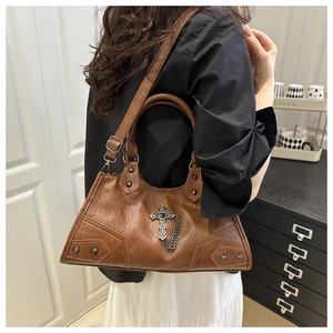 Détail d'un sac moto en similicuir marron foncé avec un pendentif en croix métallique
