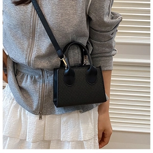 Détail du sac bandoulière noir tissé avec boucle en métal doré et poignée main