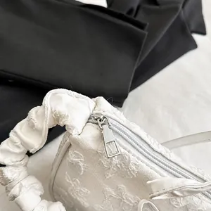 Detalle de bolso de tela blanca con textura floral 3D y cremallera metálica suave