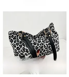 Detail of leopard print handbag with black leather handles and gold ring hardware