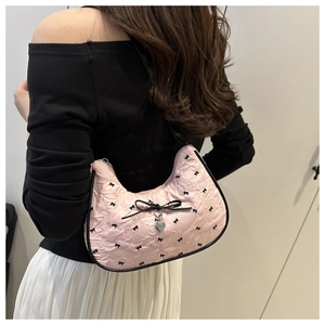 Close-up of pink hobo bag with black bow patterns and silver heart pendant detail