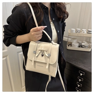 Détail du mini sac à dos en similicuir beige avec nœud décoratif et pendentif en cœur