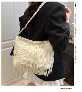 Détail du sac à bandoulière blanc à franges avec bandoulière tressée sur blazer noir