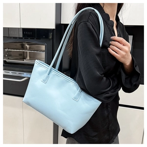 Detail of light blue leather tote bag showing large capacity and soft texture on shoulder