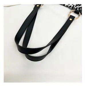Detail of comfortable black leather handle with gold rings on zebra canvas shoulder bag