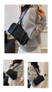 Detail of black faux leather shoulder bag featuring white contrast stitching and gold lettering