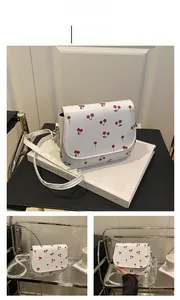Detail view of white cherry print saddle bag with slim strap and side profile