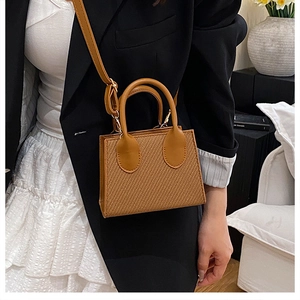 Dettaglio di una piccola borsa tote a tracolla intrecciata marrone con blazer e gonna