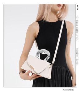 Detail of white leather handbag with unique silver fluid metallic handle and minimalist strap