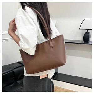 Brown large capacity tote bag shown on shoulder in a modern indoor setting
