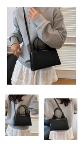 Close-up of black crocodile texture handbag with gold fashion lettering and stitching
