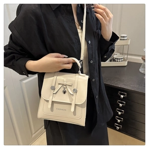 Detail view of a creamy white bow backpack with fashion lettering and heart charm on a model