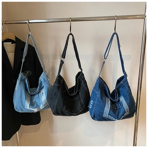 Detailed view of large denim hobo bags featuring frayed edges and adjustable straps
