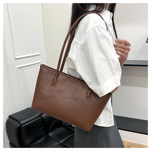 Detailed close-up of a large brown tote bag showing matte leather texture and stitching