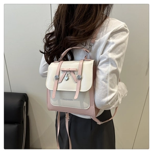 Detail of a pink and cream mini handbag featuring a bow and heart-shaped metal charm