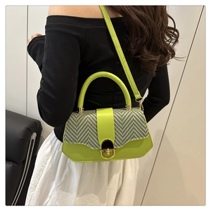 Detail of neon green geometric handbag with golden spherical lock and top handle