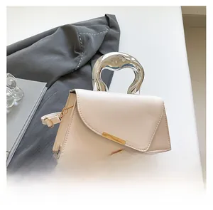 Detail of a chic cream handbag featuring a unique liquid silver metal handle and gold clasp