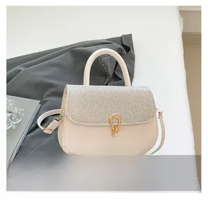Macro detail of beige crossbody bag with sparkling silver sequins and golden metal clasp