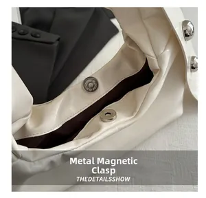 Detail of silver magnetic closure on a cream PU shoulder bag with dark brown lining